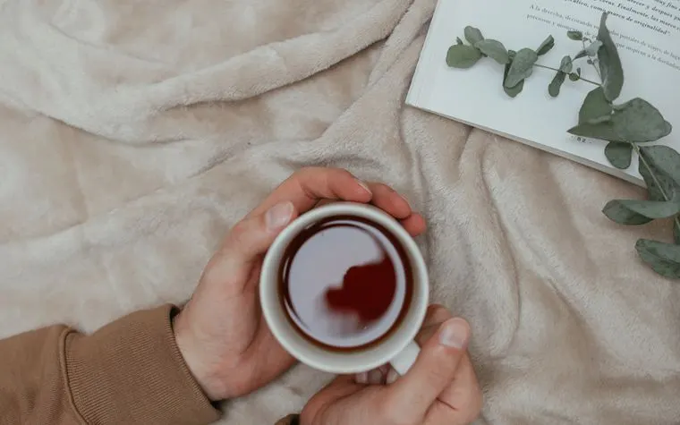 Tasse de thé chaude sur un plaid douillet à la maison