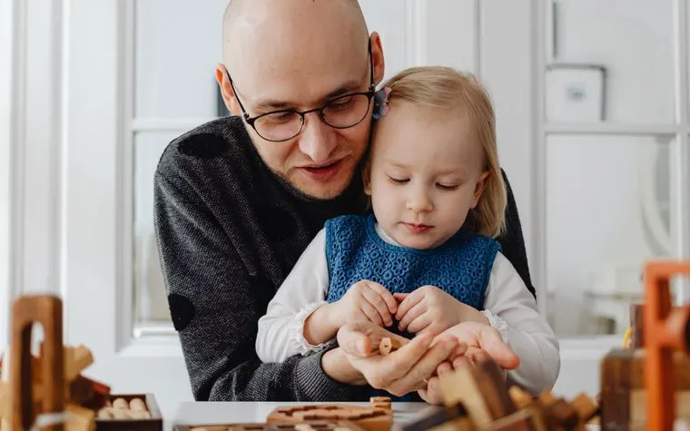 Père et fille concentrés sur un jeu en bois à la maison